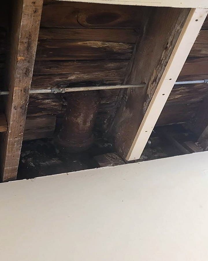 Before: Ceiling opened to water-stained joists and an old drain pipe