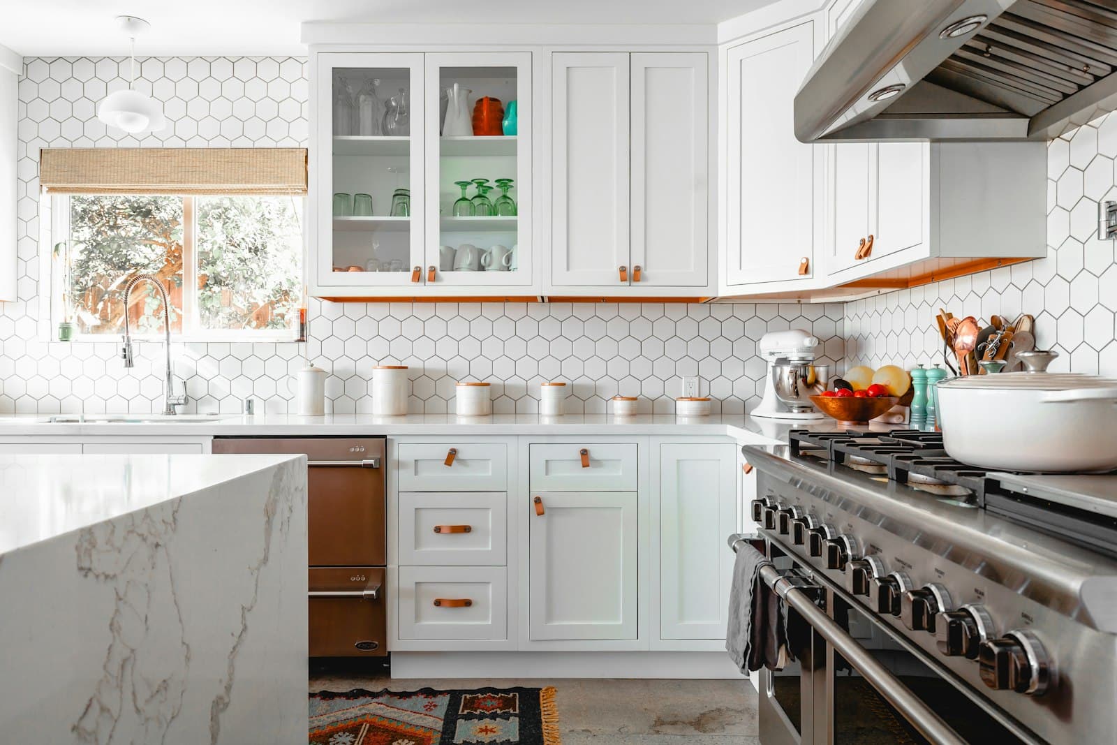 Bright kitchen with white cabinetry, marble counters, and a professional range